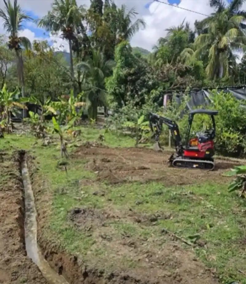 Rhinoceros mini excavator digging drainage channel in rural Honduras